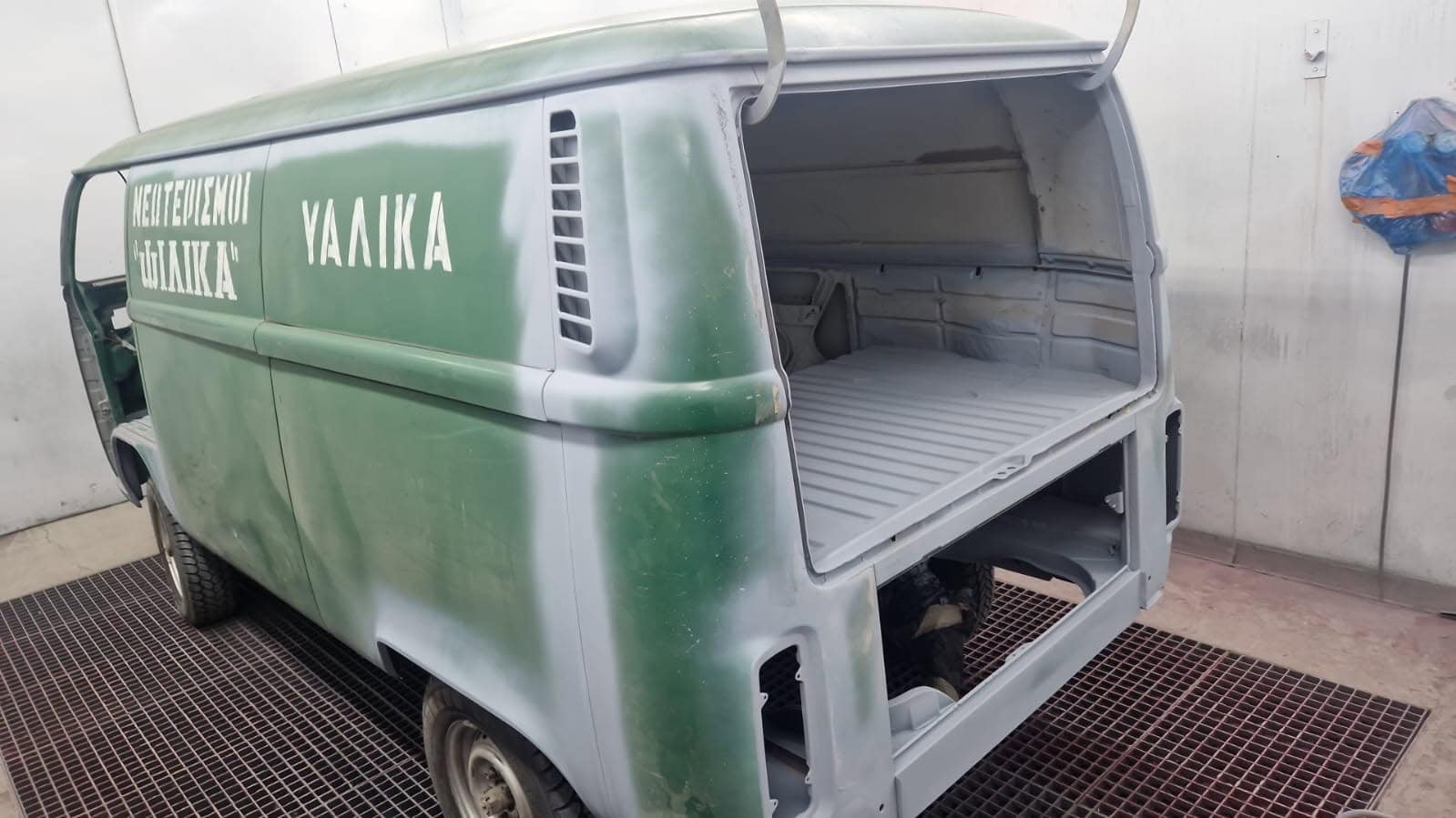 Ein grün-weißer Lieferwagen mit russischer Aufschrift steht in einer Werkstatt. Die hinteren Türen und einige Teile fehlen, sodass der Laderaum leer ist. Ein grün-weißer Lieferwagen mit russischer Aufschrift steht in einer Werkstatt. Die hinteren Türen und einige Teile fehlen, sodass der Laderaum leer ist.
